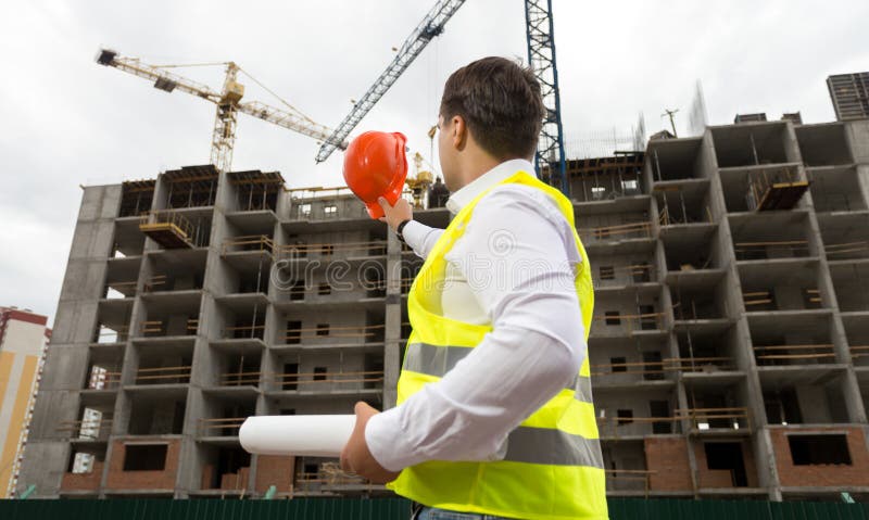 Potomstwo inżyniera mienia projekty i wskazywać przy placem budowy zdjęcie stock