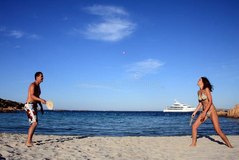 Potomstwo para bawić się tenisa na plaży. obraz royalty free Potomstwo para bawić się tenisa na plaży. obraz royalty free