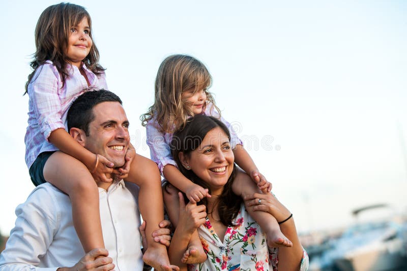 Close up portrait of young couple with kids on shoulders at sunset. Close up portrait of young couple with kids on shoulders at sunset.