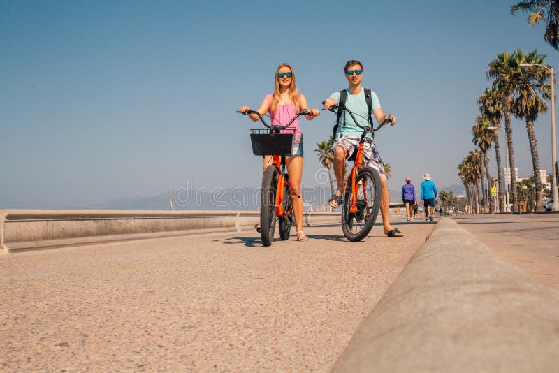 Potomstwo pary jeździeccy bicykle zestrzelają Wenecja plażę w Los Angeles zdjęcia stock Potomstwo pary jeździeccy bicykle zestrzelają Wenecja plażę w Los Angeles zdjęcia stock