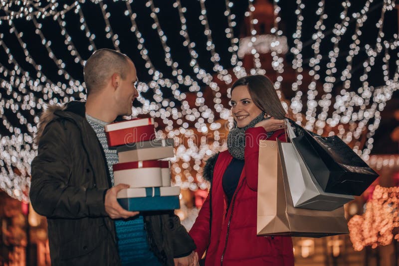 Potomstwo pary mienia teraźniejszość w pudełku i torbach przy nocą obrazy stock Potomstwo pary mienia teraźniejszość w pudełku i torbach przy nocą obrazy stock