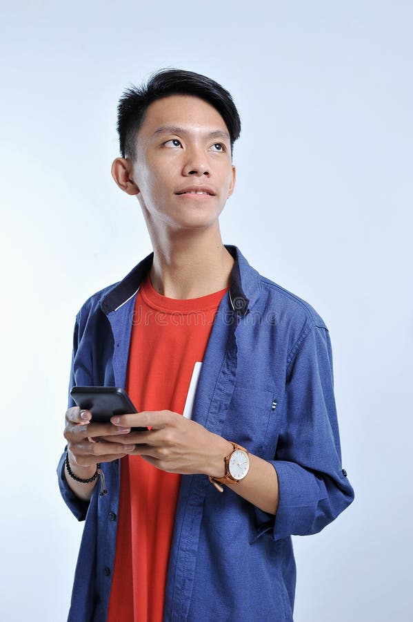 Potrait di giovane uomo asiatico bello che tiene uno Smart Phone ed indossare orologio con lo sguardo sorridente grazioso allo sp immagine stock libera da diritti Potrait di giovane uomo asiatico bello che tiene uno Smart Phone ed indossare orologio con lo sguardo sorridente grazioso allo sp immagine stock libera da diritti