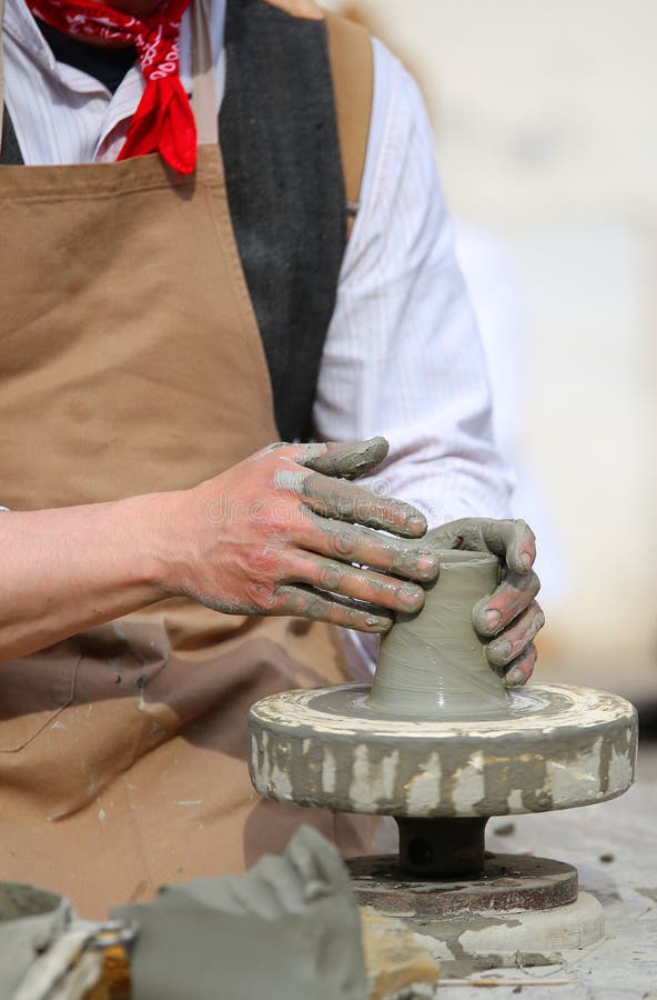 Potter with the hand lathe during production of a pot with clay