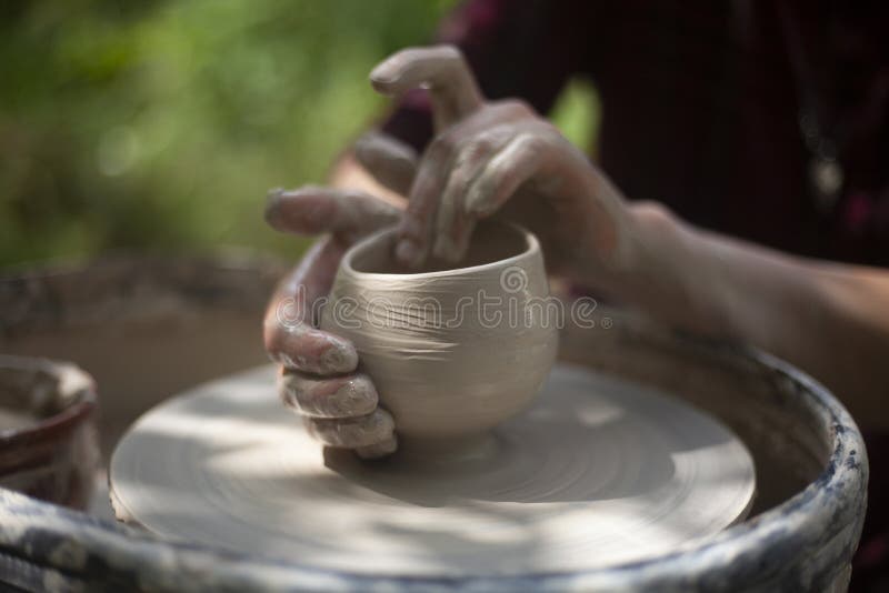 Hands of a potter sculpt clay dishes on a pottery wheel. Folk craft for  making dishes.