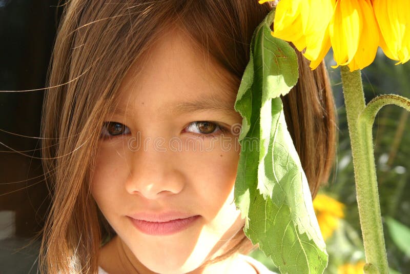 Sweet eight year old girl taking shade under huge sunflower against the raging sun. Fit for sunny disposition, optimism, fresh ideas, innovation, takecover, etc. concepts. Sweet eight year old girl taking shade under huge sunflower against the raging sun. Fit for sunny disposition, optimism, fresh ideas, innovation, takecover, etc. concepts.