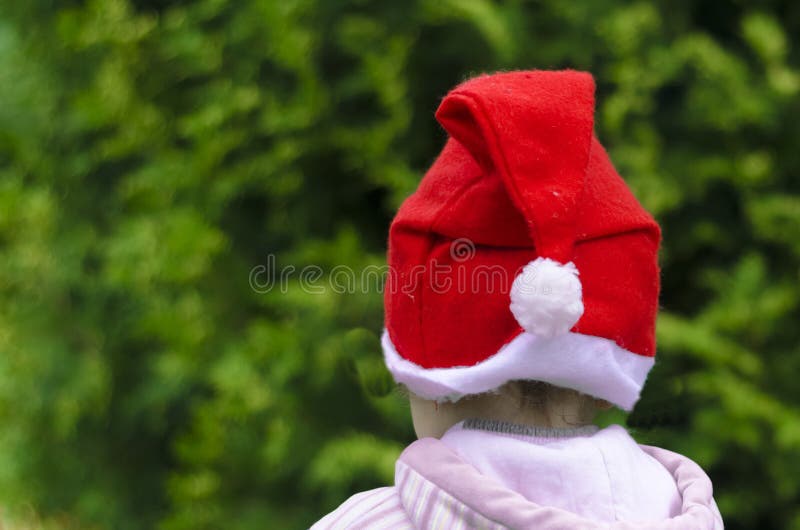 Pouco criança no chapéu de Santa em um fundo verde decore uma árvore de Natal Feriados de inverno Esperando o ano novo fotografia de stock Pouco criança no chapéu de Santa em um fundo verde decore uma árvore de Natal Feriados de inverno Esperando o ano novo fotografia de stock