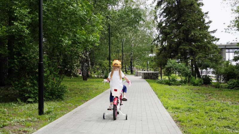 Pouco menina bonito que aprecia montando sua bicicleta fora