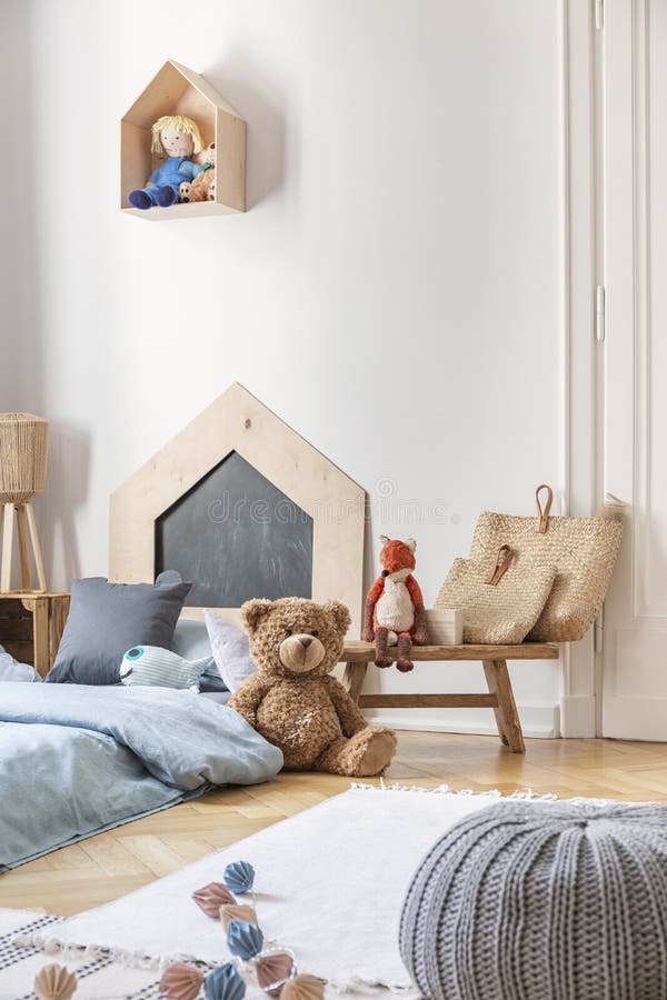 Pouf, tappeto, giocattoli e letto con lettiera blu nella camera da letto del ragazzino alla moda, foto reale immagini stock libere da diritti Pouf, tappeto, giocattoli e letto con lettiera blu nella camera da letto del ragazzino alla moda, foto reale immagini stock libere da diritti