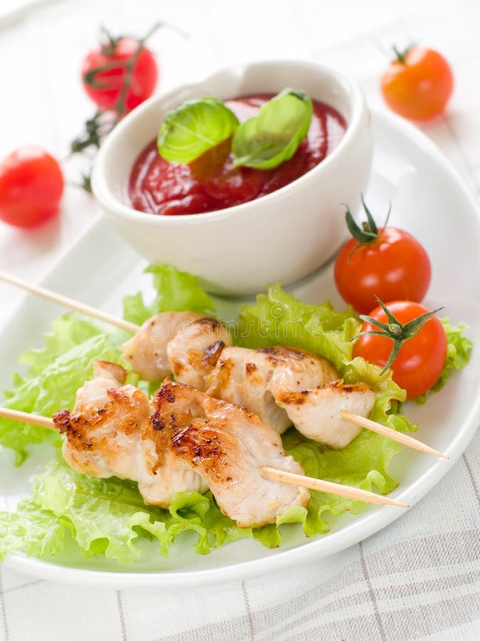 Chicken (or pork) on a grill spit with salad and bowl of ketchup. Chicken (or pork) on a grill spit with salad and bowl of ketchup