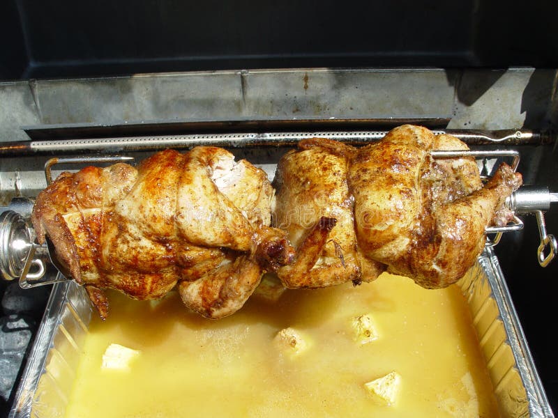 Two whole chickens on a spit roast over a pineapple marinade. Two whole chickens on a spit roast over a pineapple marinade