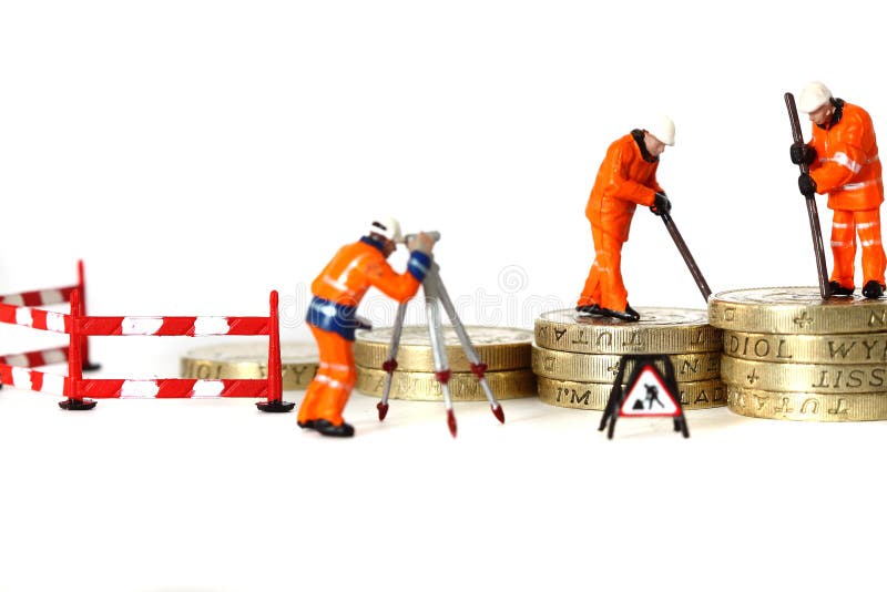 Photograph of miniature construction figures stacking pound coins. Building savings concept. Photograph of miniature construction figures stacking pound coins. Building savings concept.