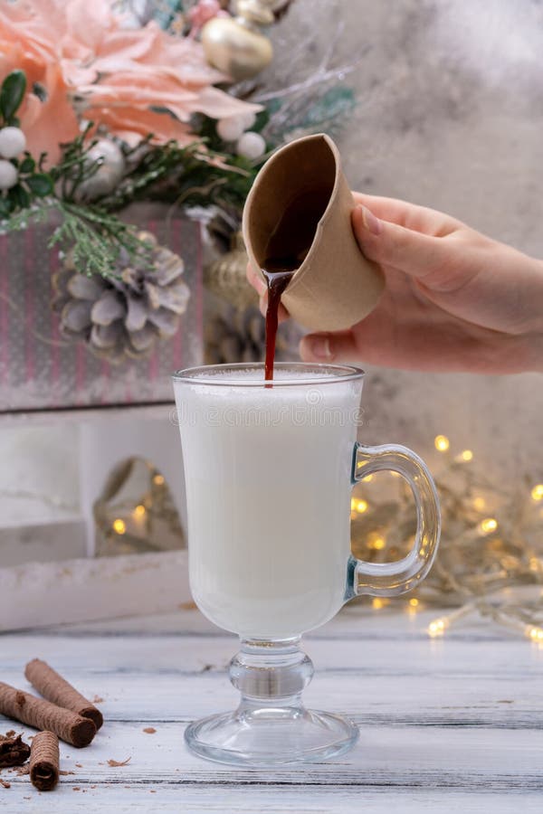 Pour Espresso into Whipped Milk in Irish Cup on Christmas Background