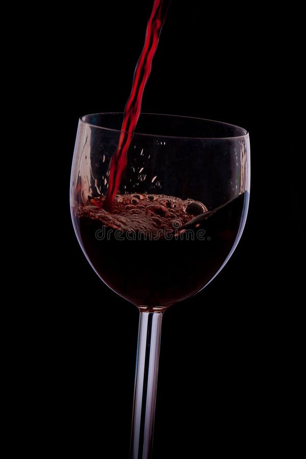 Pour the wine into the glass on a black background