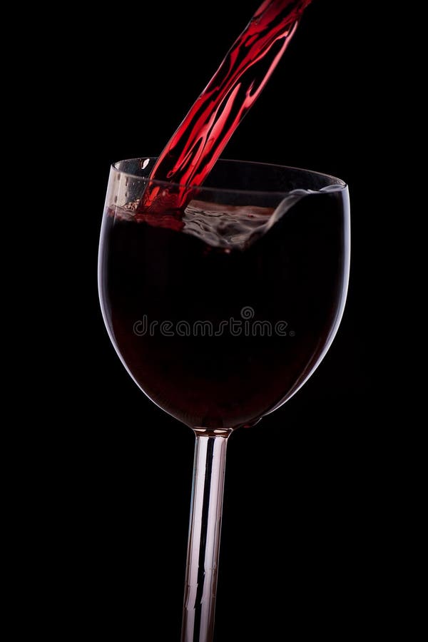 Pour the wine into the glass on a black background