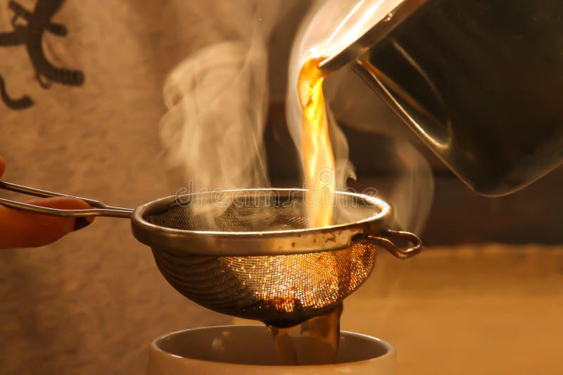 Pouring Green Tea from the Pot into a Cup with a Strainer Stock Image