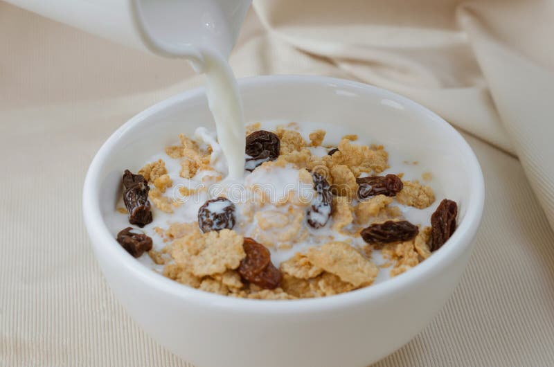 Pouring Milk in Bowl of Cereal and Raisin for Breakfast Meal. Stock ...