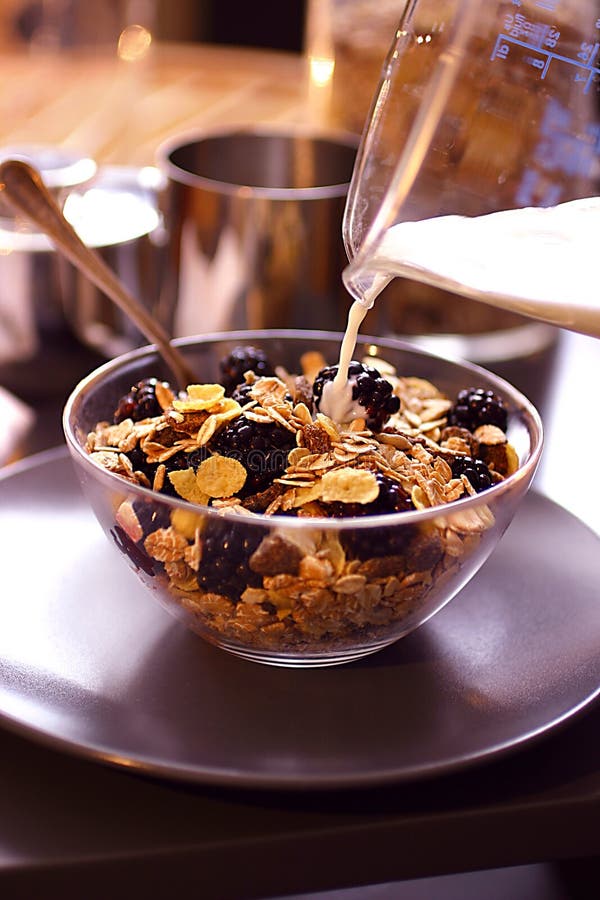 Pouring milk over cornflakes with blackberries