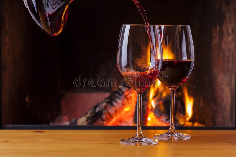 Pouring red wine at cozy fireplace royalty free stock photography Pouring red wine at cozy fireplace royalty free stock photography