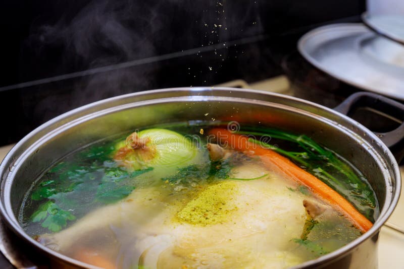 Pouring Seasoning into Boiling Chicken Broth with Vegetables in Steel