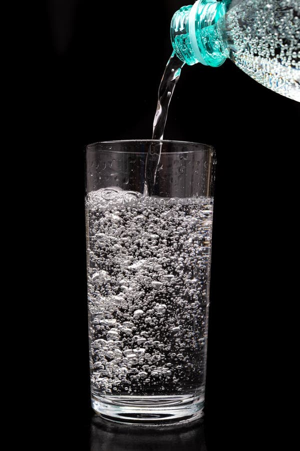 Pouring sparkling water from a bottle into a glass. Refreshing mineral water in a glass dish