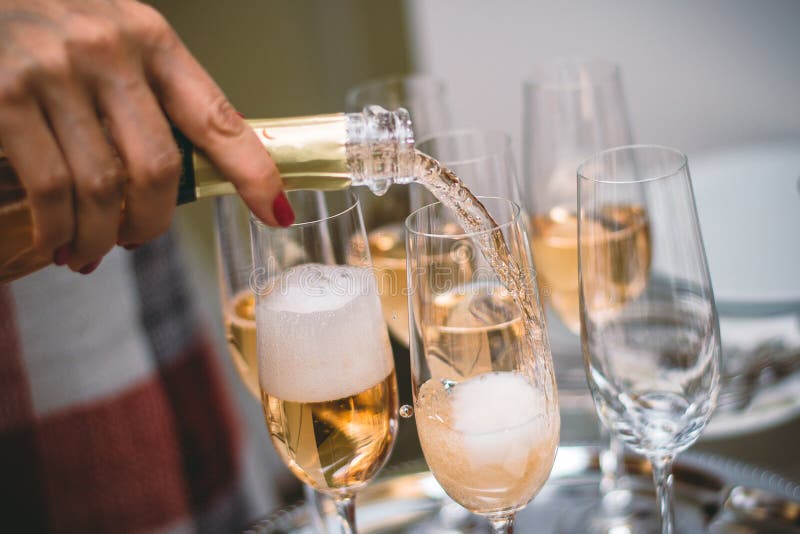 Pouring sparkling yellow champagne on wine glasses.