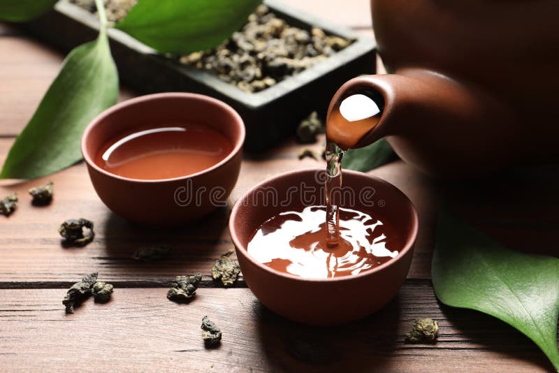 Pouring Tie Guan Yin oolong tea into cup on table