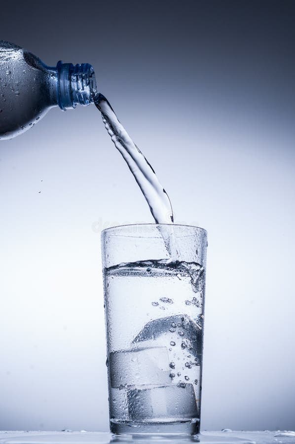 Pouring water from bottle into glass on blue background royalty free stock photography Pouring water from bottle into glass on blue background royalty free stock photography