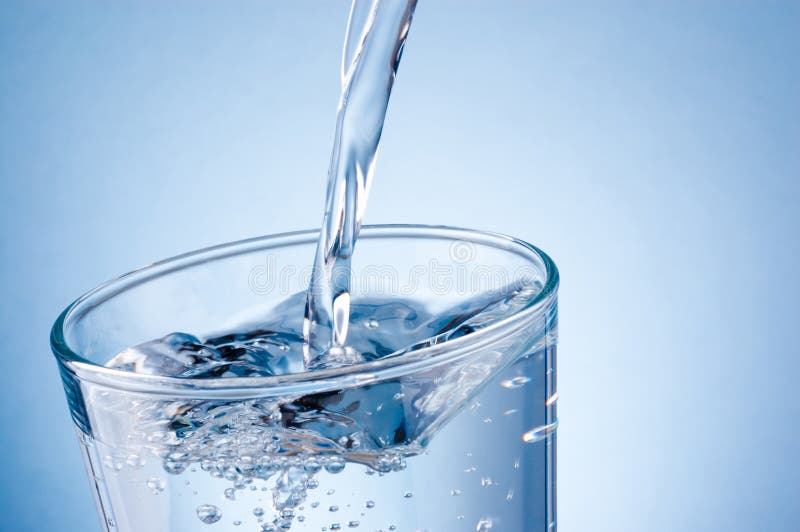 Pouring water into glass on blue background royalty free stock photo Pouring water into glass on blue background royalty free stock photo
