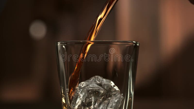 Pouring Whisky into the Glass over an Ice Cube