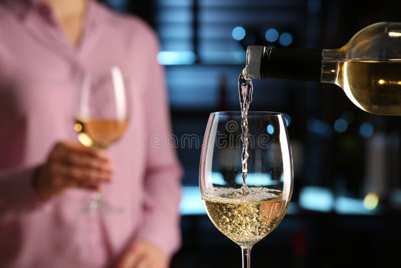 Pouring White Wine from Bottle into Glass in Bar, Closeup. Space for
