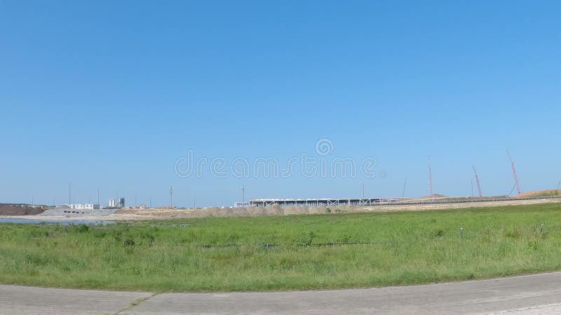 Pov drive street pan área masiva de construcción con docenas de grúas cielo azul despejado