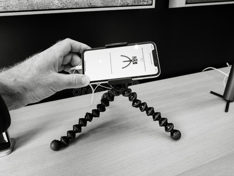 Paris, France - Mar 19 2019: POV man holding iPhone XS on the Joby Gorillapod tripod on the accessories stand inside minimalist and luxury design of Apple Store Champs-Elysees largest French store - black and whtie