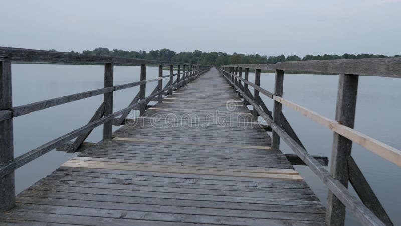 POV van een persoon die alleen door een oude houten pijler of een brug over rivier lopen Kalmte en ontspanning