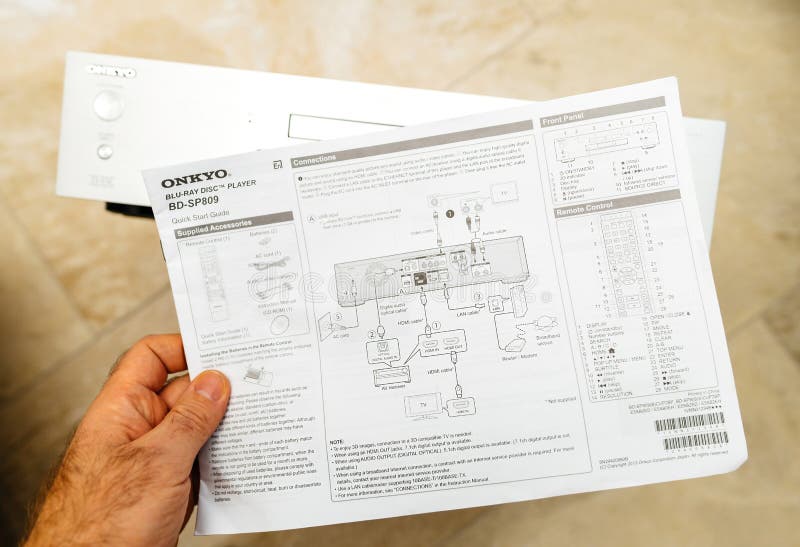 Paris, France - Oct 18, 2023: POV male hand holding paper with quick start guide connection modes manual of Onkyo BD-SP809 top-of-the-range Blu-ray deck. Paris, France - Oct 18, 2023: POV male hand holding paper with quick start guide connection modes manual of Onkyo BD-SP809 top-of-the-range Blu-ray deck