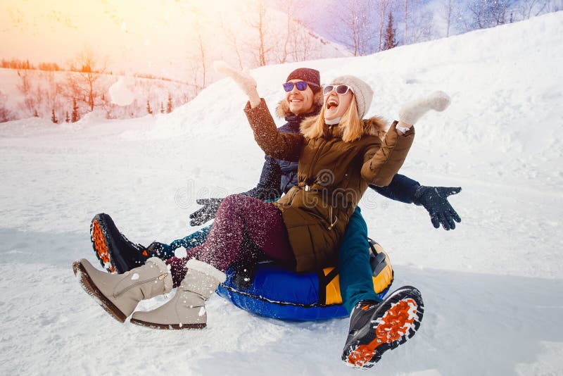 Povos felizes no tubo fora nas montanhas na neve do inverno imagem de stock Povos felizes no tubo fora nas montanhas na neve do inverno imagem de stock
