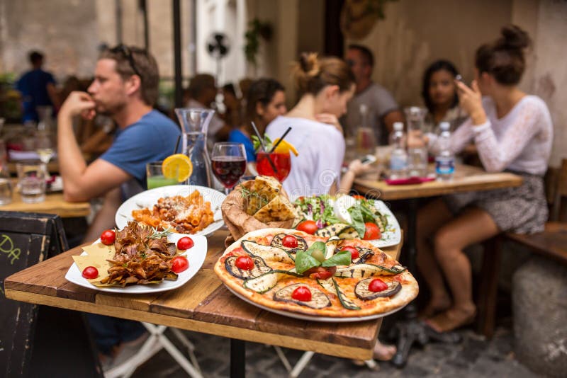 Povos não identificados que comem o alimento italiano tradicional no restaurante exterior imagem de stock