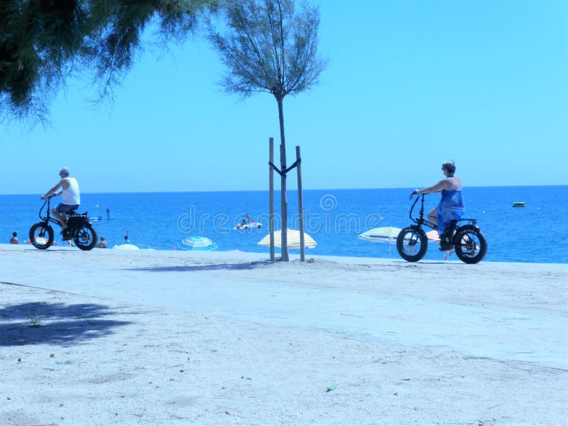 Povos que montam bicicletas elétricas na praia foto de stock royalty free Povos que montam bicicletas elétricas na praia foto de stock royalty free