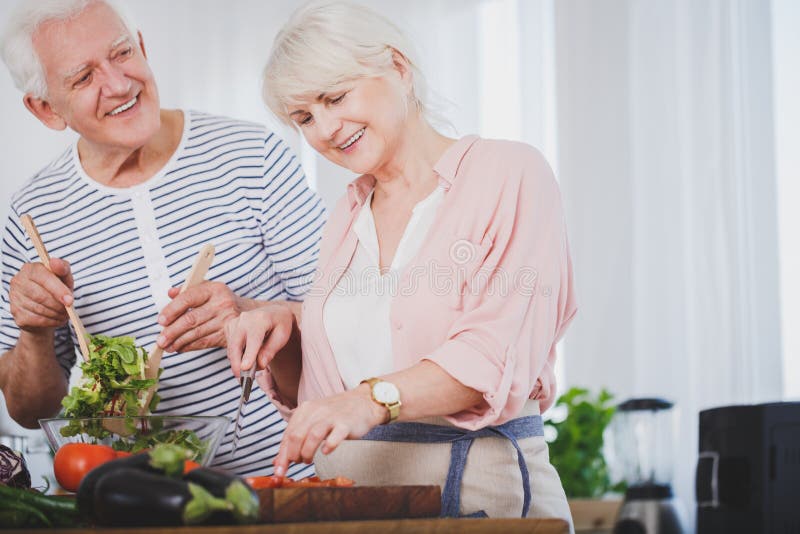 Povos superiores de sorriso que preparam a salada imagens de stock Povos superiores de sorriso que preparam a salada imagens de stock