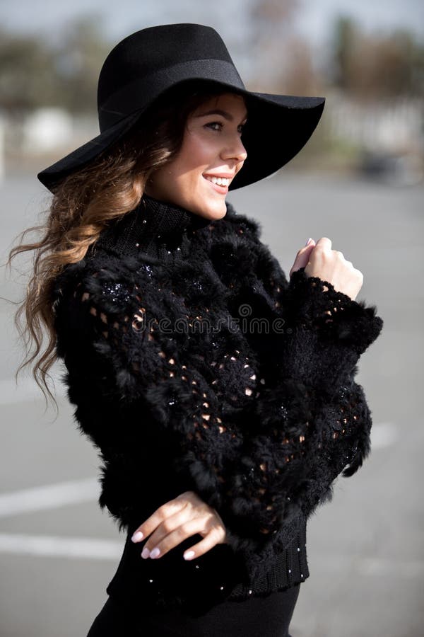 Powabna elegancka brunetki dziewczyna ubiera? w eleganckim trykotowym czarnym pulowerze z futerkiem, czer? kapeluszem z, sp?dnico fotografia stock Powabna elegancka brunetki dziewczyna ubiera? w eleganckim trykotowym czarnym pulowerze z futerkiem, czer? kapeluszem z, sp?dnico fotografia stock