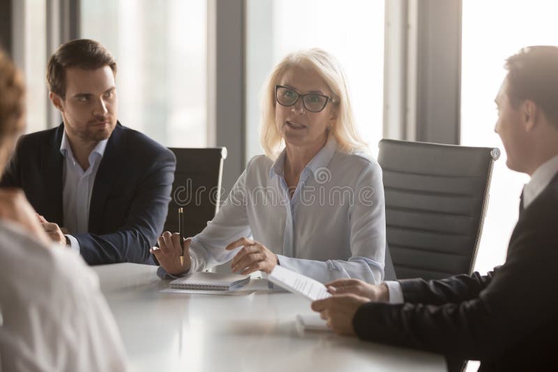 Poważne w średnim wieku bizneswoman rozmowy przy grupą wsiadają wykonawczego spotkania zdjęcia royalty free Poważne w średnim wieku bizneswoman rozmowy przy grupą wsiadają wykonawczego spotkania zdjęcia royalty free