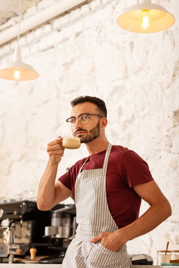 Poważny biznesmen pijący cappuccino w swojej kawiarni fotografia stock