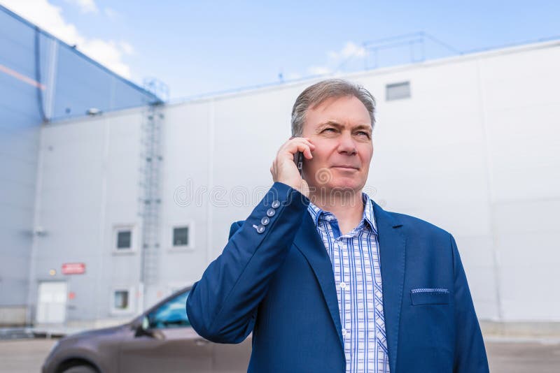 Poważny biznesmen w średnim wieku w niebieskim garniturze dzwoniący przez telefon Ulica, na zewnątrz obraz stock Poważny biznesmen w średnim wieku w niebieskim garniturze dzwoniący przez telefon Ulica, na zewnątrz obraz stock
