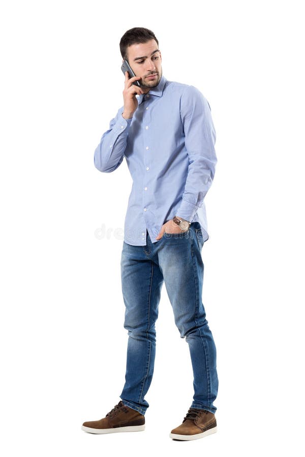 Poważny młody skeptical biznesmen opowiada na telefonie przyglądającym z powrotem zdjęcia stock Poważny młody skeptical biznesmen opowiada na telefonie przyglądającym z powrotem zdjęcia stock