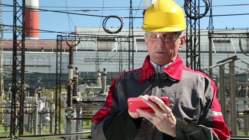 Power engineering specialist with red smartphone at electropower station
