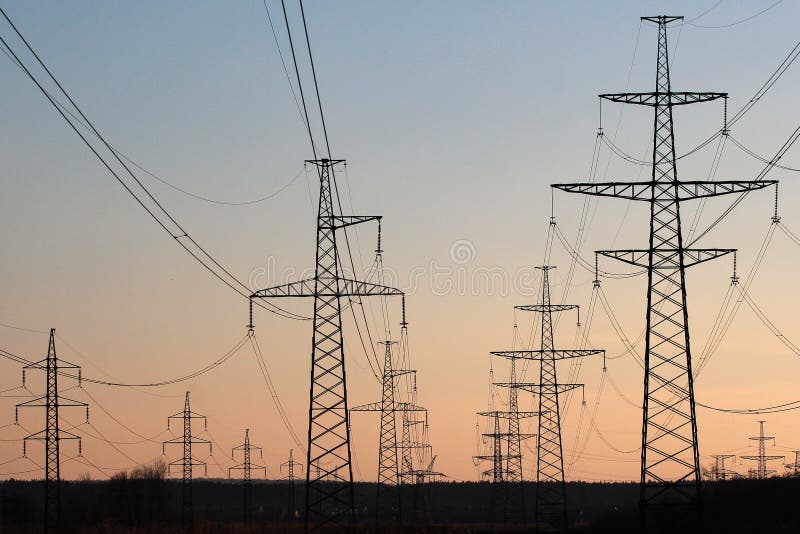Power line pylons against sunset sky background