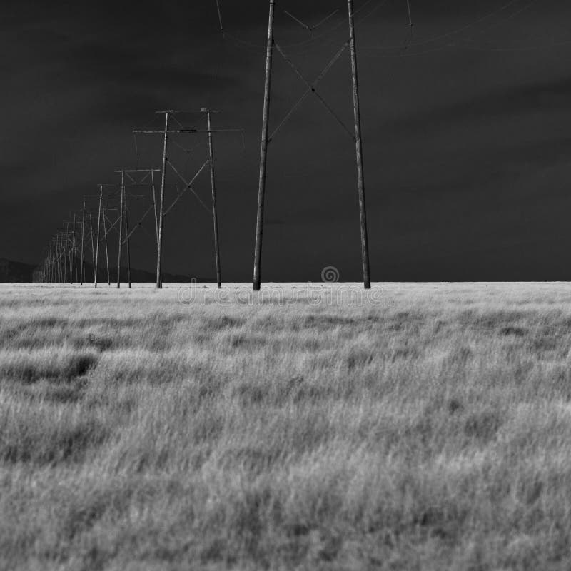 A silhouette of high voltage power lines against a dramatic and dark sky. Red pylons stock images, royalty-free photos and pictures