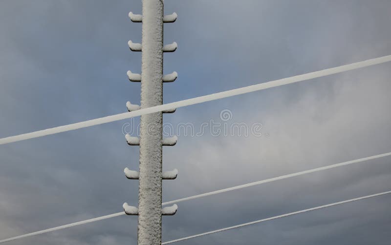 Power lines frozen by a large layer of ice layer in the shape of a cylinder with icicles. icing burdens the poles, ladder and ligh royalty free stock image