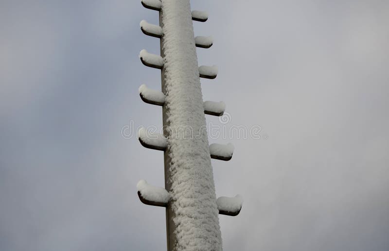 Power lines frozen by a large layer of ice layer in the shape of a cylinder with icicles. icing burdens the poles, ladder and ligh stock photo