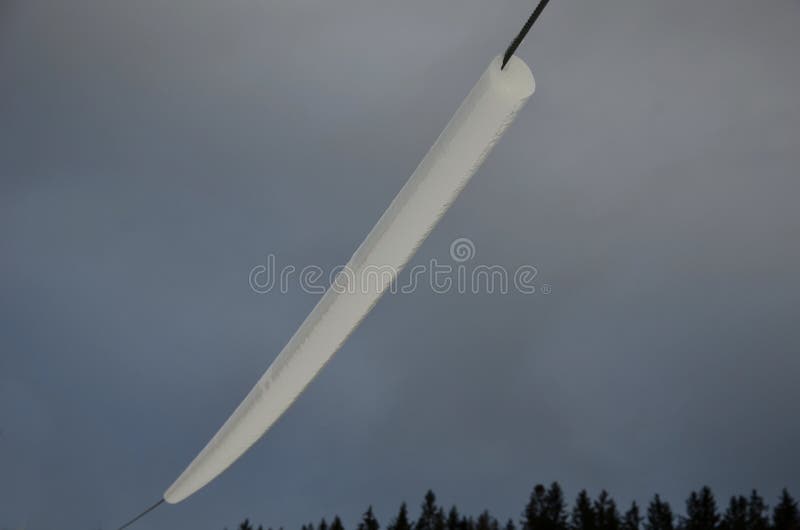 Power lines frozen by a large layer of ice in the shape of a cylinder with icicles. icing loads the columns, which are overloaded stock images