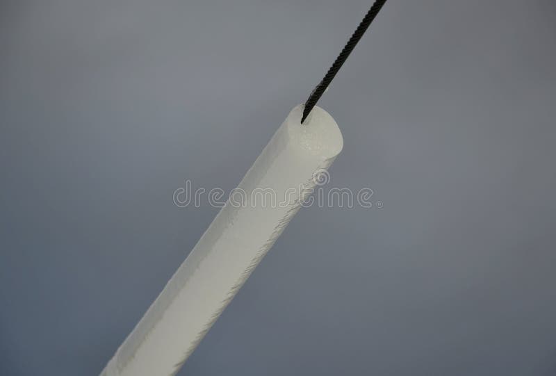 Power lines frozen by a large layer of ice in the shape of a cylinder with icicles. icing loads the columns, which are overloaded stock photo